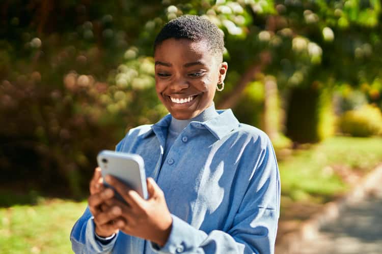 Imagem mulher sorrindo enquanto olha o celular